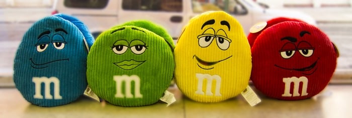 Four M&M's pillows in a row on windowsill