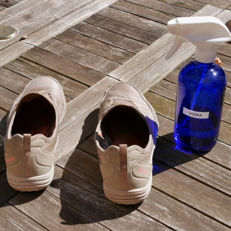 Sneakers next to a blue glass spray bottle labeled "Vodka".