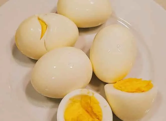 Five hard-boiled eggs on a white, one egg split in half