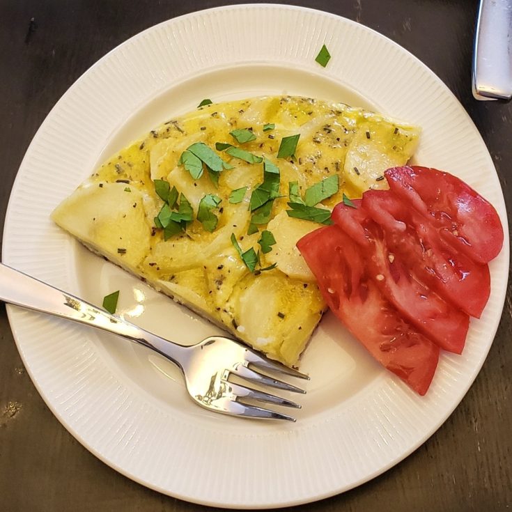 Frittata and tomato slices on a plate.