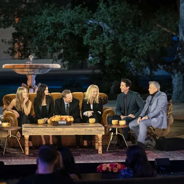 Jennifer Anniston, Courteney Cox, Matthew Perry, Lisa Kudrow, David Schwimmer, and Matt LeBlanc sitting together on a couch and chairs.