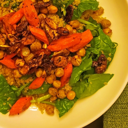 Carrots, chickpeas, and spinach with quinoa in a shallow bowl, garnished with a lime wedge.