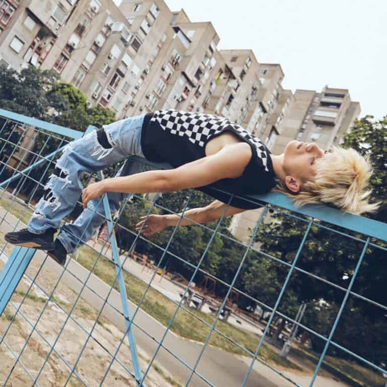Teen lying on fence, looking despondent.