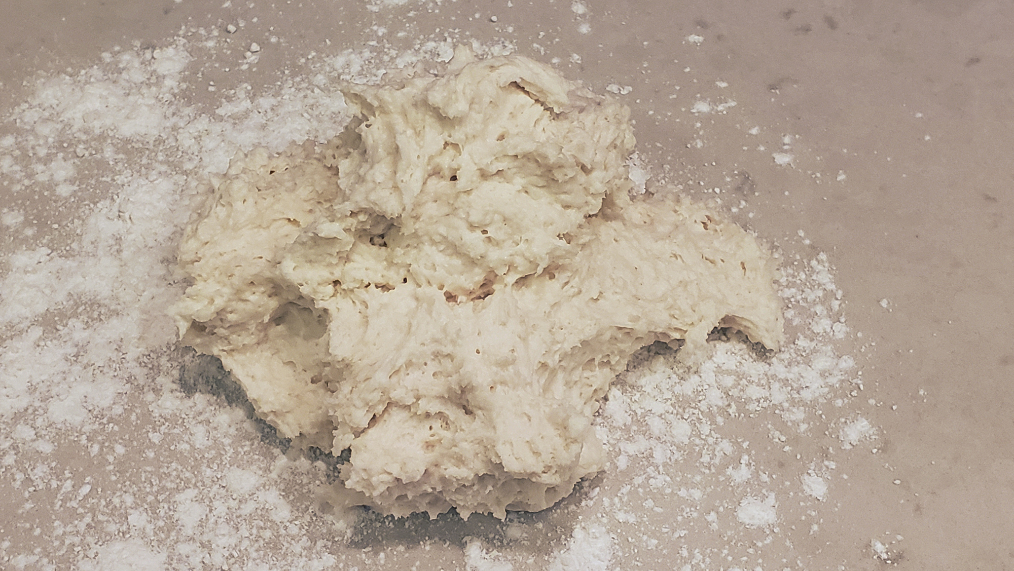 Sticky, shaggy biscuit dough on a floured counter.