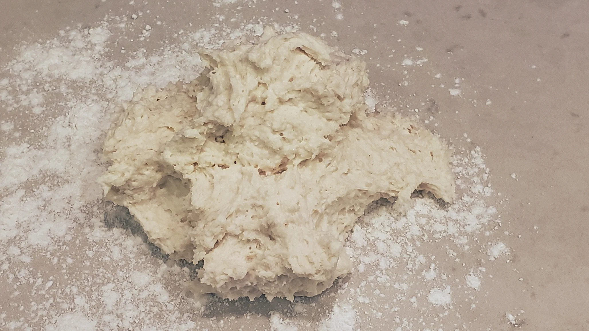 Sticky, shaggy biscuit dough on a floured counter.