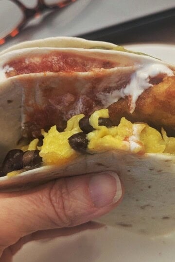 A delicious breakfast tortilla sandwich being eaten.