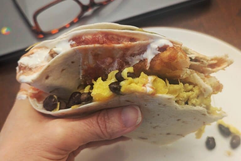 A delicious breakfast tortilla sandwich being eaten.