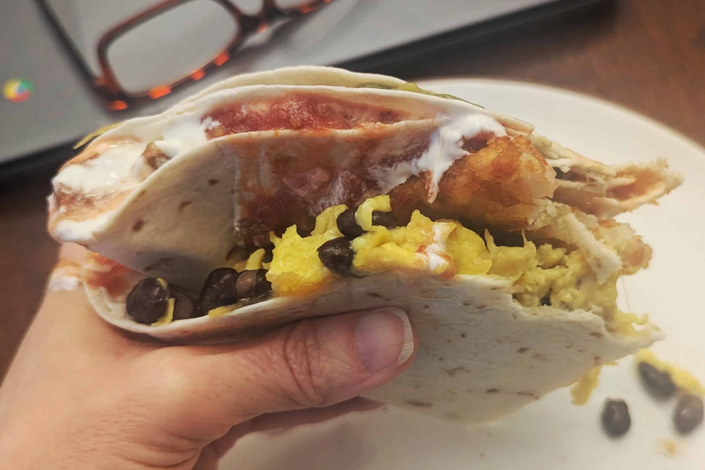 A delicious breakfast tortilla sandwich being eaten.