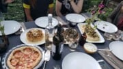A table outdoors set with plates, wine, and food.
